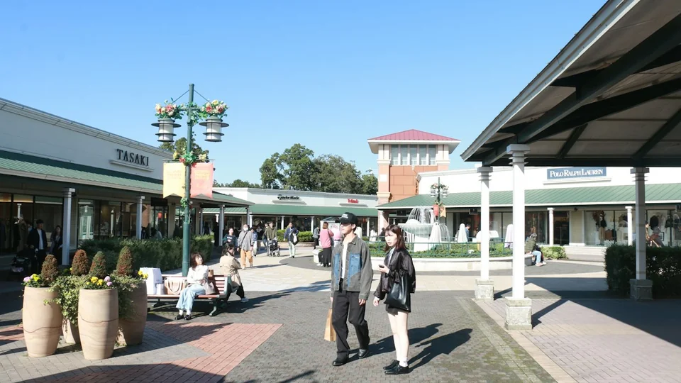 Open-air shopping center with storefronts, planters, a fountain and a paved pedestrian walkway